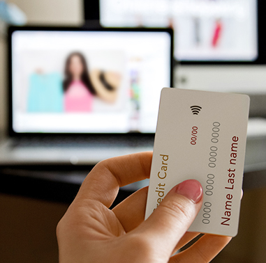 Women holding credit card up in front of computer